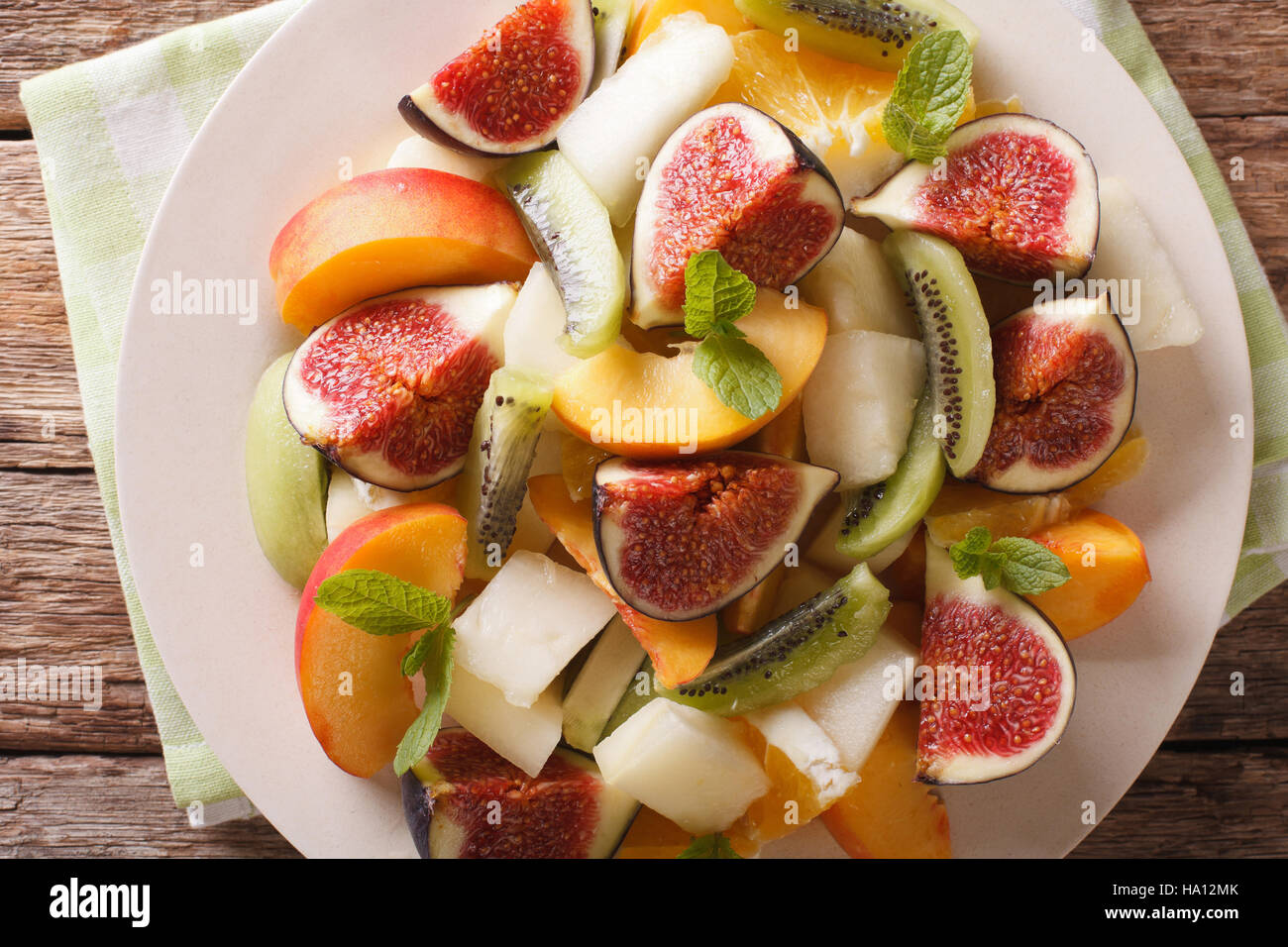 Salad of ripe fruit: figs, peaches, melons, kiwi and orange close-up on a plate. Horizontal view from above Stock Photo