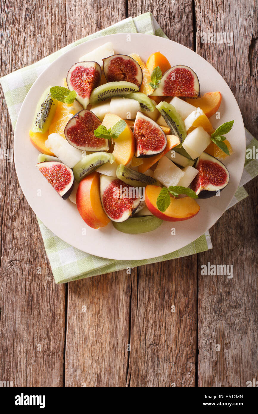 Healthy Fruit salad with fig, peach, melon, kiwi and orange close-up on the table. vertical view from above Stock Photo