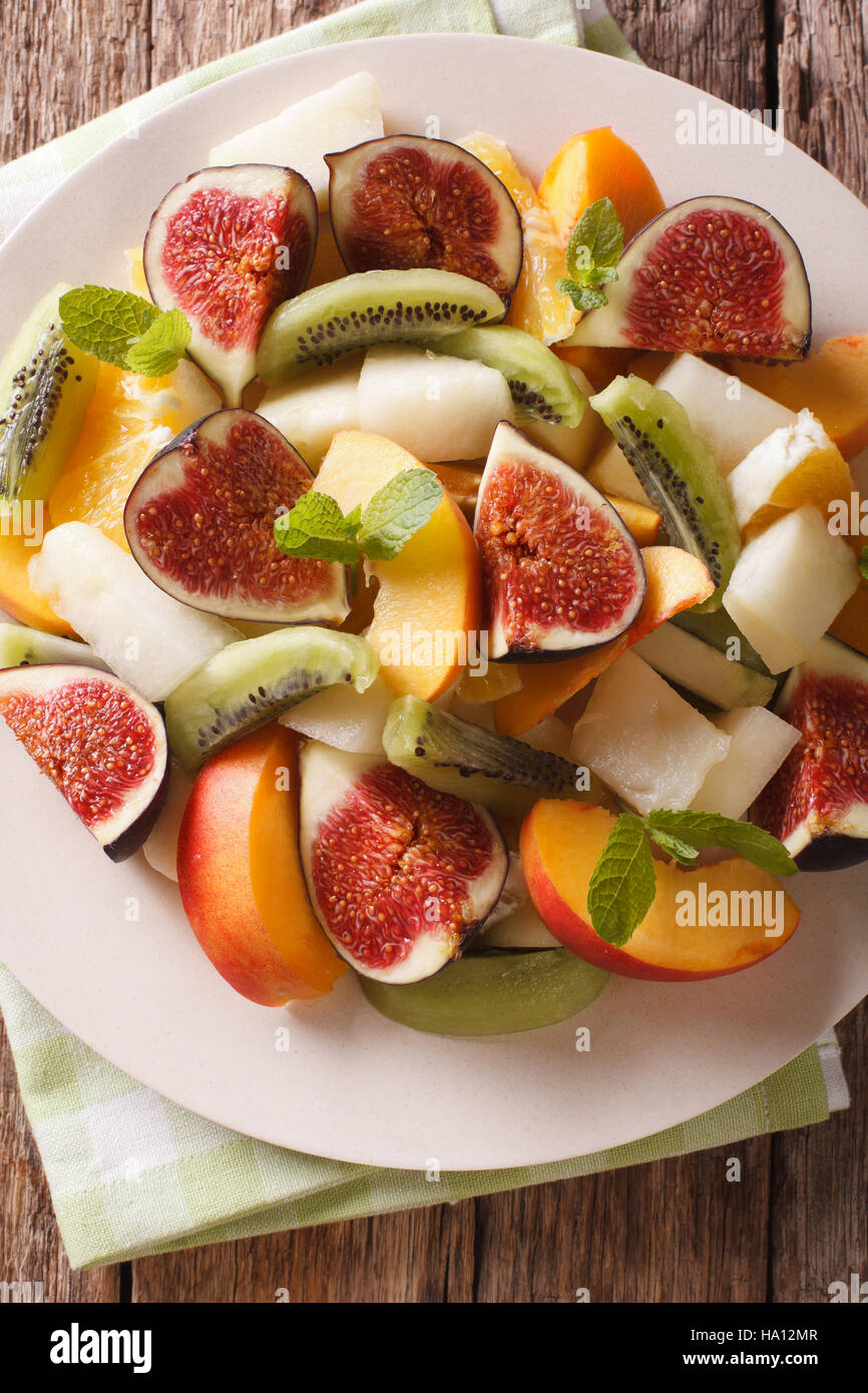 Salad of ripe fruit: figs, peaches, melons, kiwi and orange close-up on a plate. vertical view from above Stock Photo