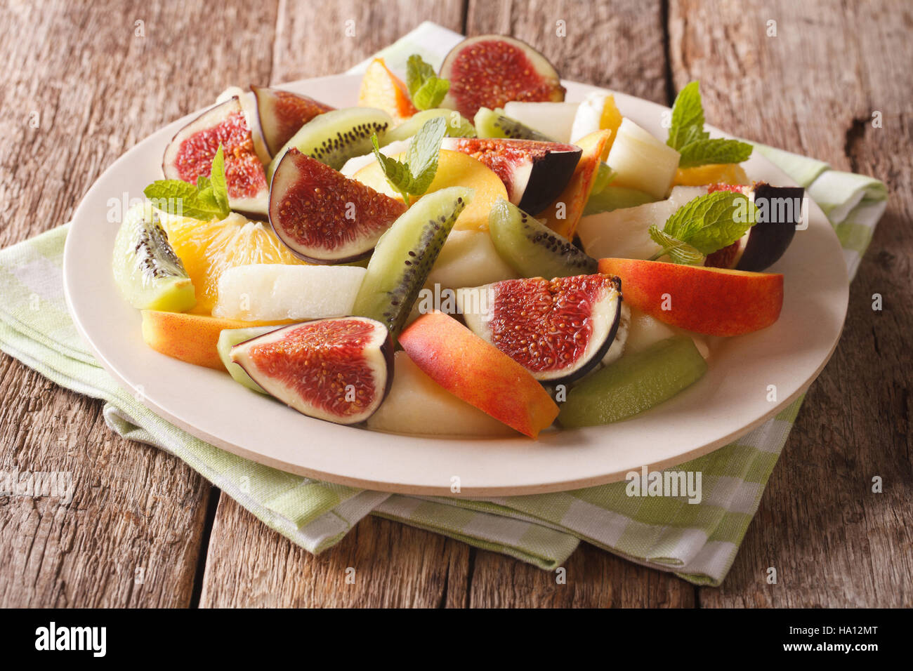Salad of ripe fruit: figs, peaches, melons, kiwi and orange close-up on a plate. horizontal Stock Photo
