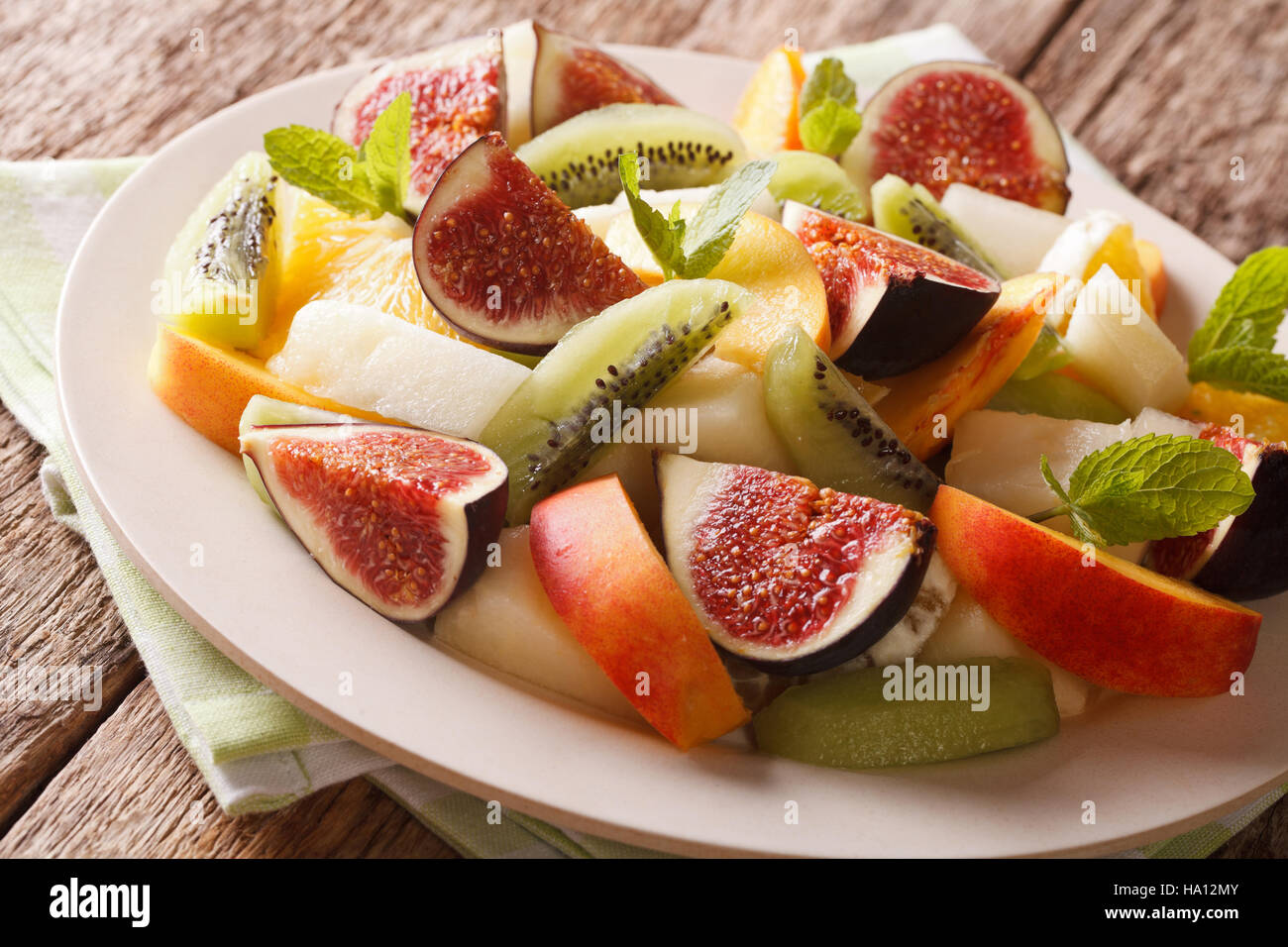 Fresh fruit salad of figs, peaches, melons, kiwi and orange close-up on a plate. horizontal Stock Photo