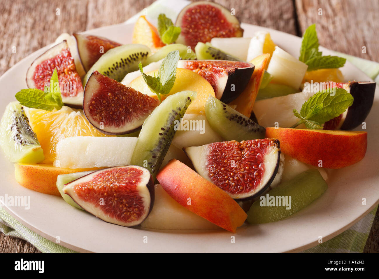 Fresh summer fruit salad with fig, peach, melon, kiwi and orange close-up on the table. horizontal Stock Photo