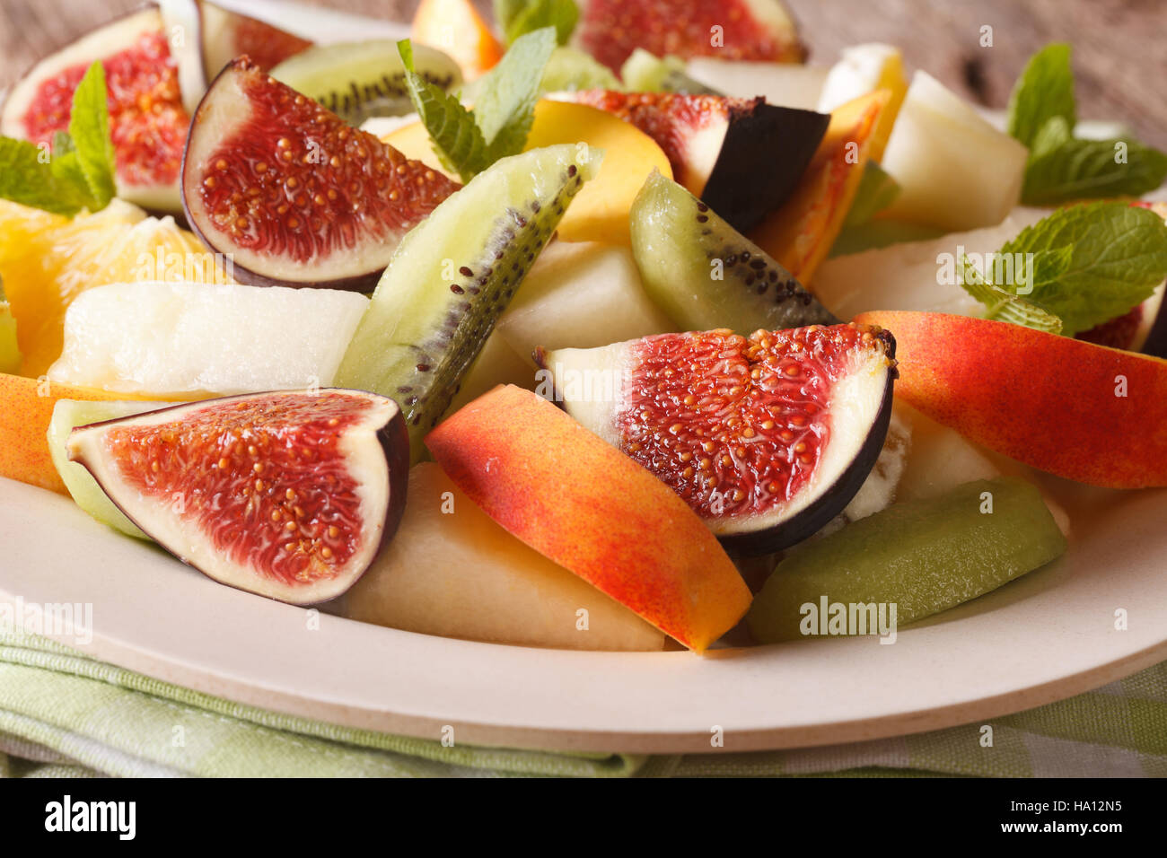 Sliced fresh fruit: figs, peaches, melons, kiwi and orange close-up on a plate. horizontal Stock Photo
