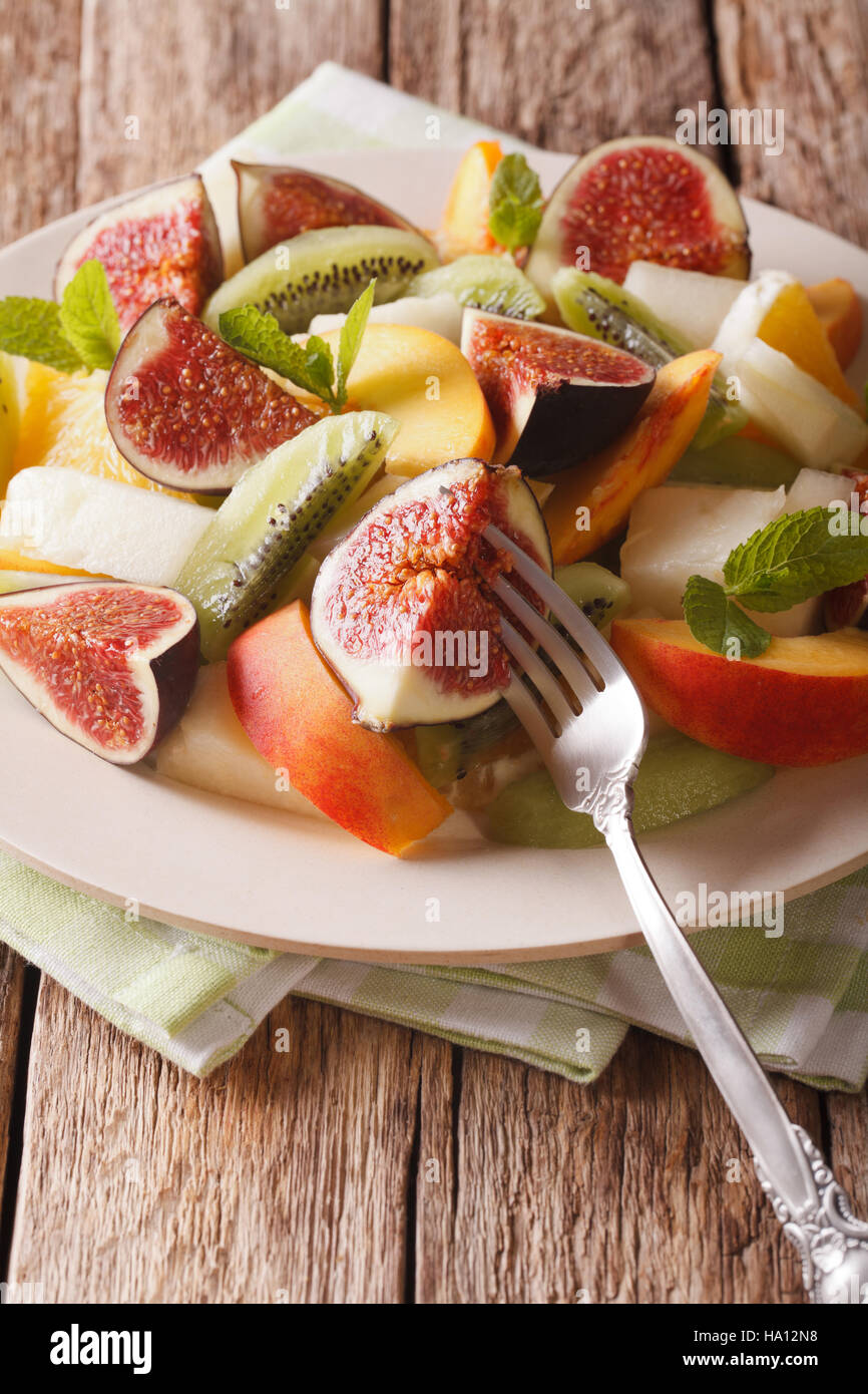 Healthy Fruit salad with fig, peach, melon, kiwi and orange close-up on the table. vertical Stock Photo