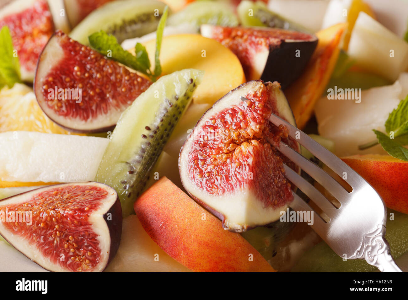 Background of fresh fruit salad with fig, peach, melon, kiwi and orange close-up. horizontal Stock Photo