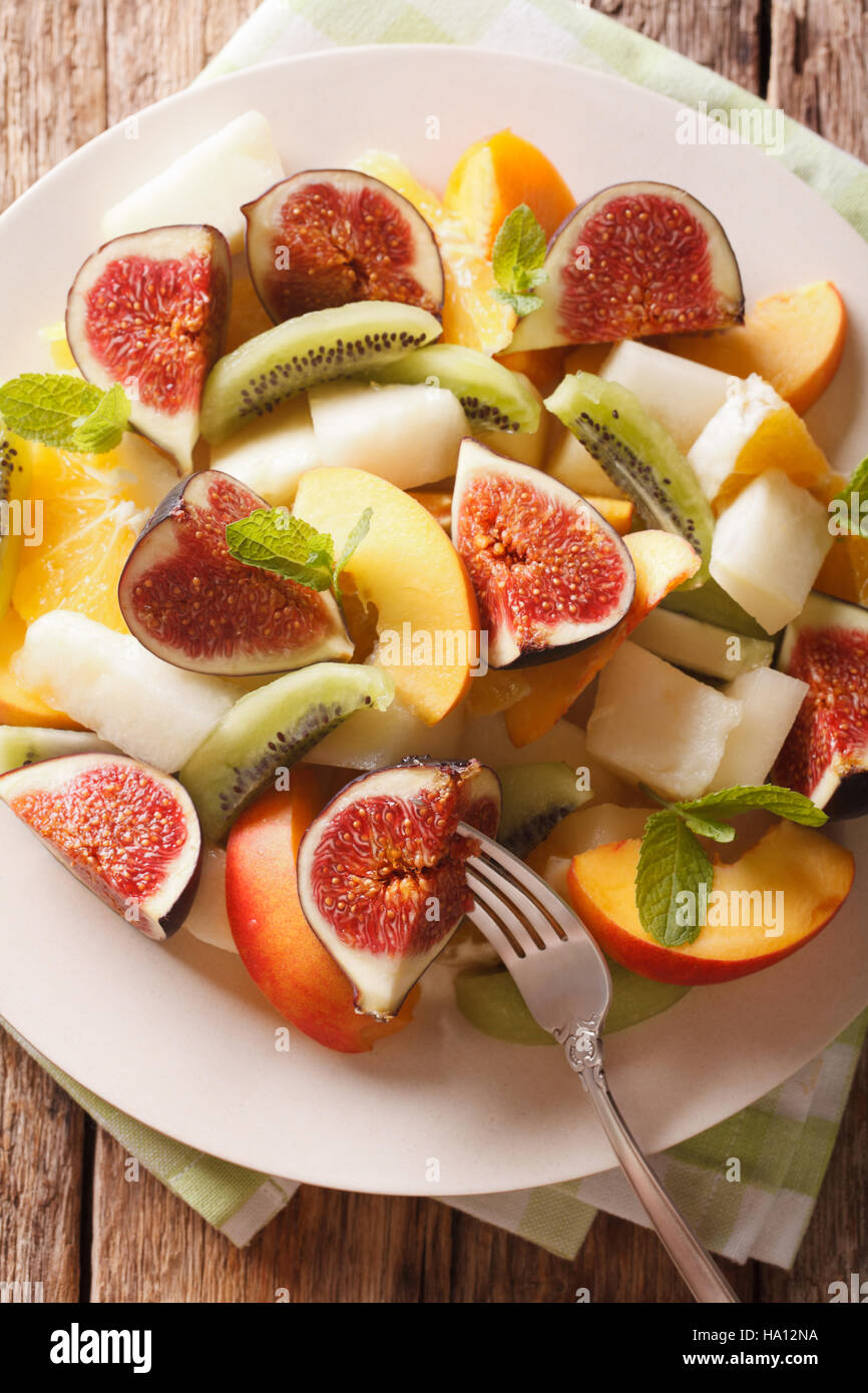 Fruit salad with fig, peach, melon, kiwi and orange close-up on a plate. vertical view from above Stock Photo