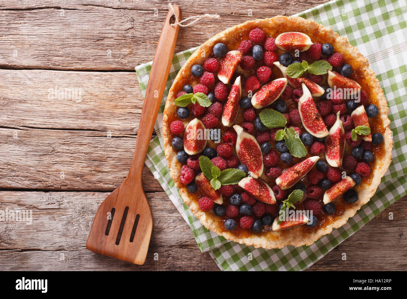 Freshly baked cake with fresh figs, raspberries and blueberries on the table. Horizontal view from above Stock Photo