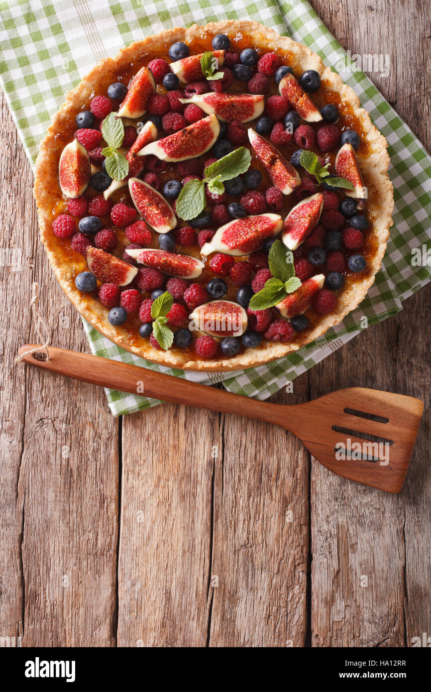 Freshly baked cake with fresh figs, raspberries and blueberries on the table. Vertical view from above Stock Photo