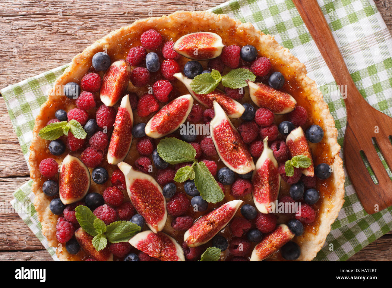 Delicious pastry: tart with fresh figs, raspberries and blueberries close-up on the table. Horizontal view from above Stock Photo