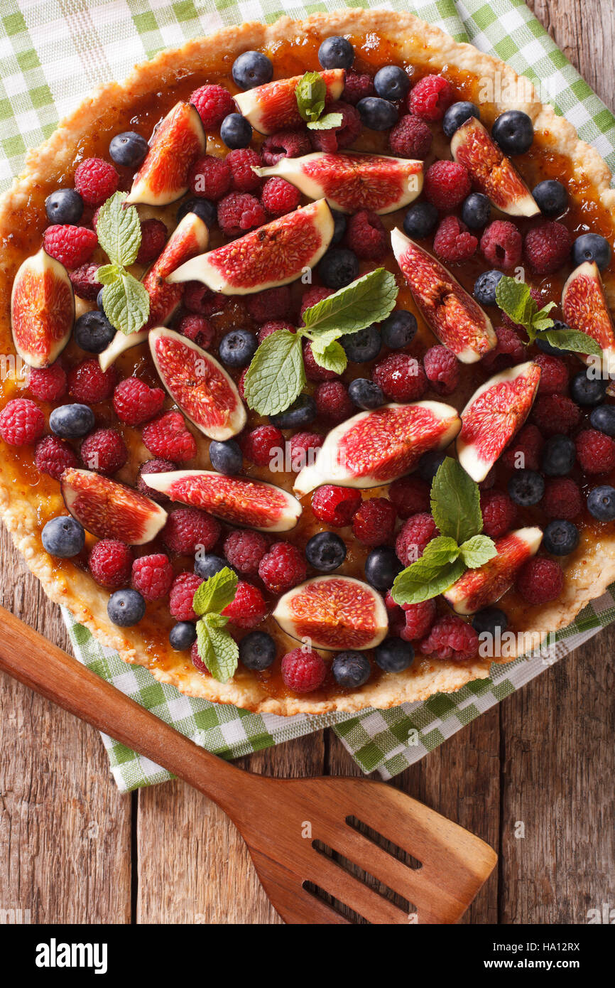 tart with figs, raspberries and blueberries macro on the table. vertical view from above Stock Photo