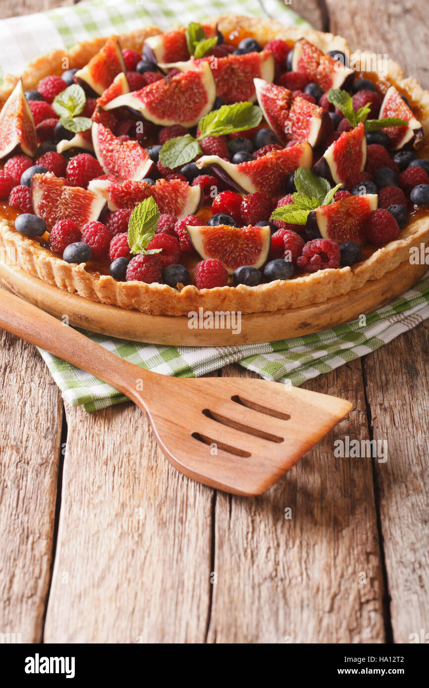 Summer cake with fresh figs, raspberries and blueberries close-up on the table. Vertical Stock Photo
