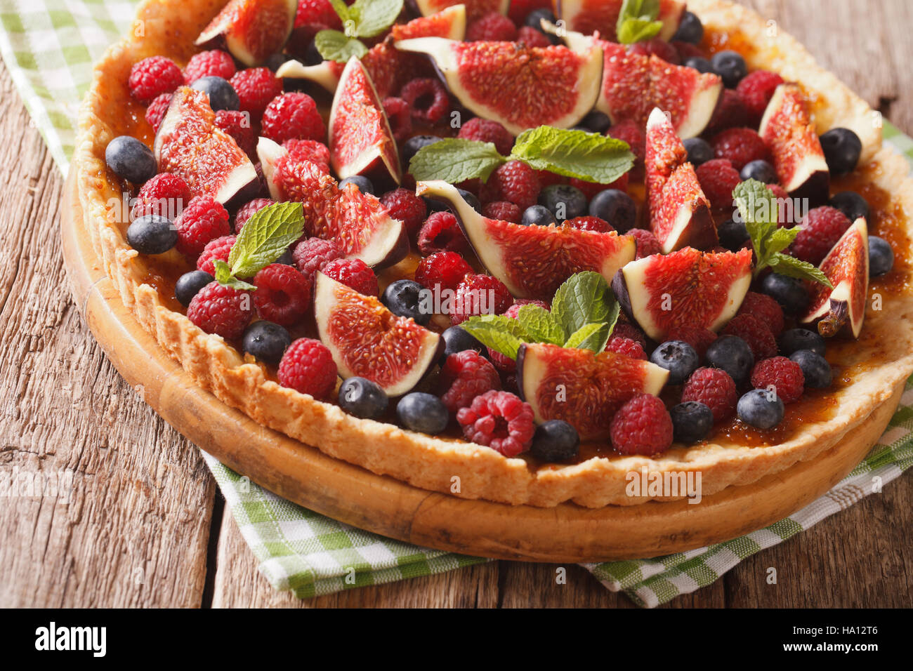 Delicious pastry: tart with fresh figs, raspberries and blueberries close-up on the table. horizontal Stock Photo
