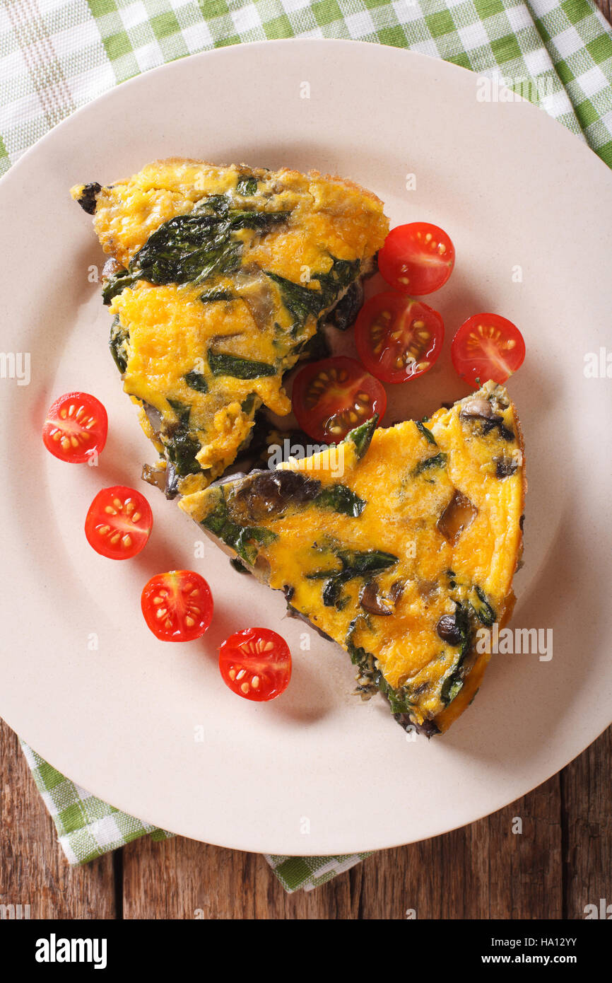 Frittata with spinach and mushrooms on a plate close-up. vertical view from above Stock Photo