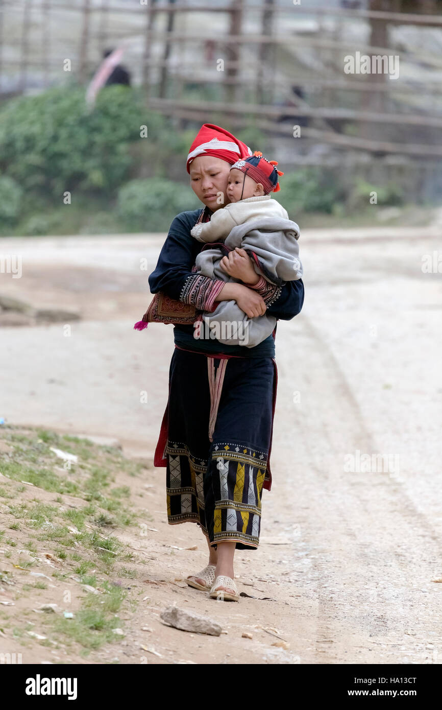 ethnic Red Dzao woman carrying her baby in Ta Phin, Lao Cai in Sapa, Vietnam, Asia Stock Photo