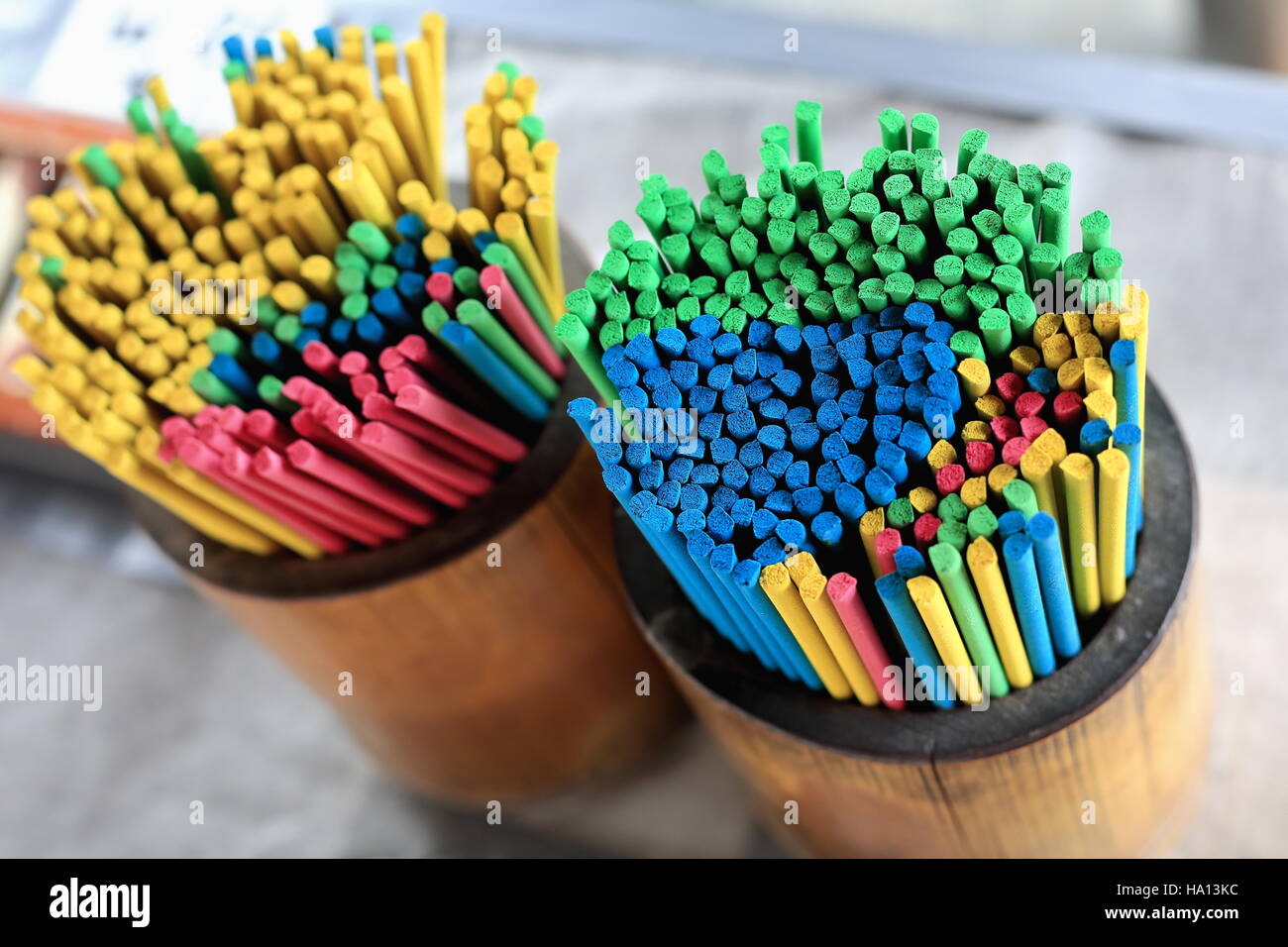 Multi-colored incense sticks placed in wooden cylindrical pannikins for sale to the devotees visiting the Hase-dera or Hasse-Kannon buddhist temple in Stock Photo