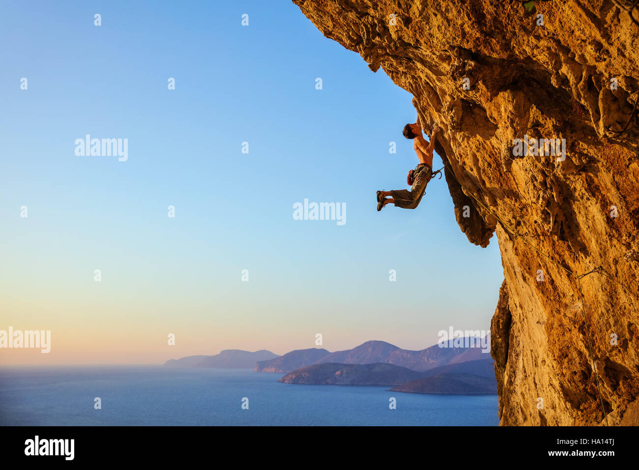 Rock climber jumping on handholds while climbing overhanging cliff