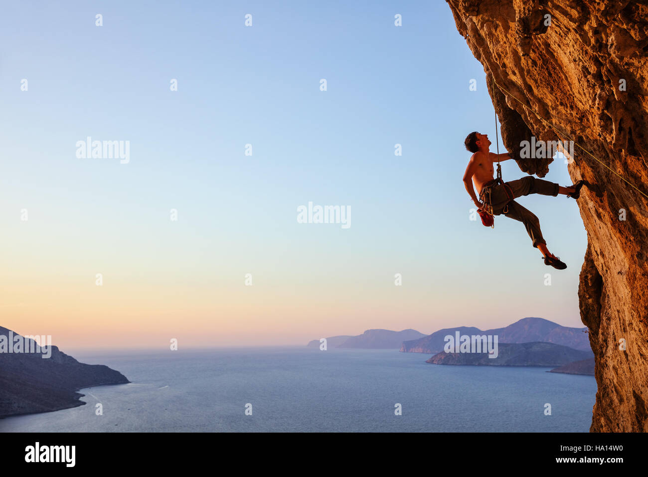 Rock climber resting while climbing overhanging cliff Stock Photo