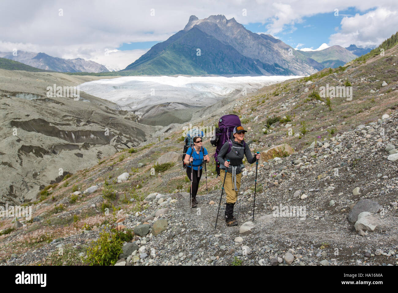 This image shows backpackers trekking along the Root Glacier Trail in ...