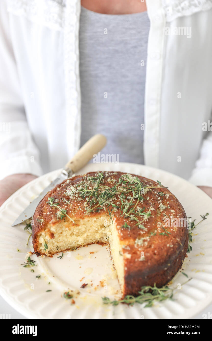 Woman holding Lemon and Thyme Syrup Cake with slice missing Stock Photo