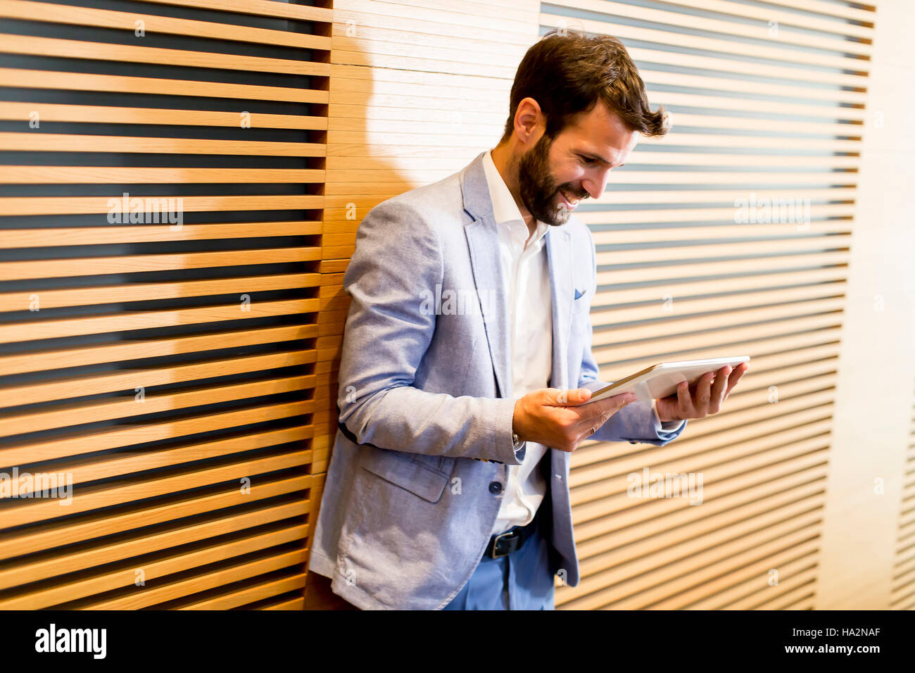 Smiling young businessman using his digital tablet at the office Stock ...