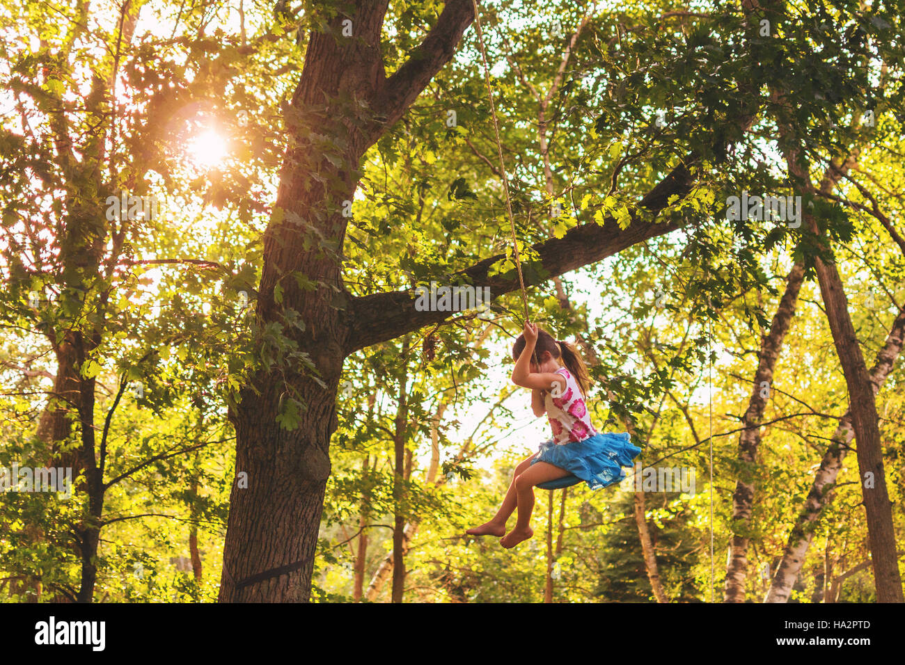Girl swinging on a rope swing Stock Photo