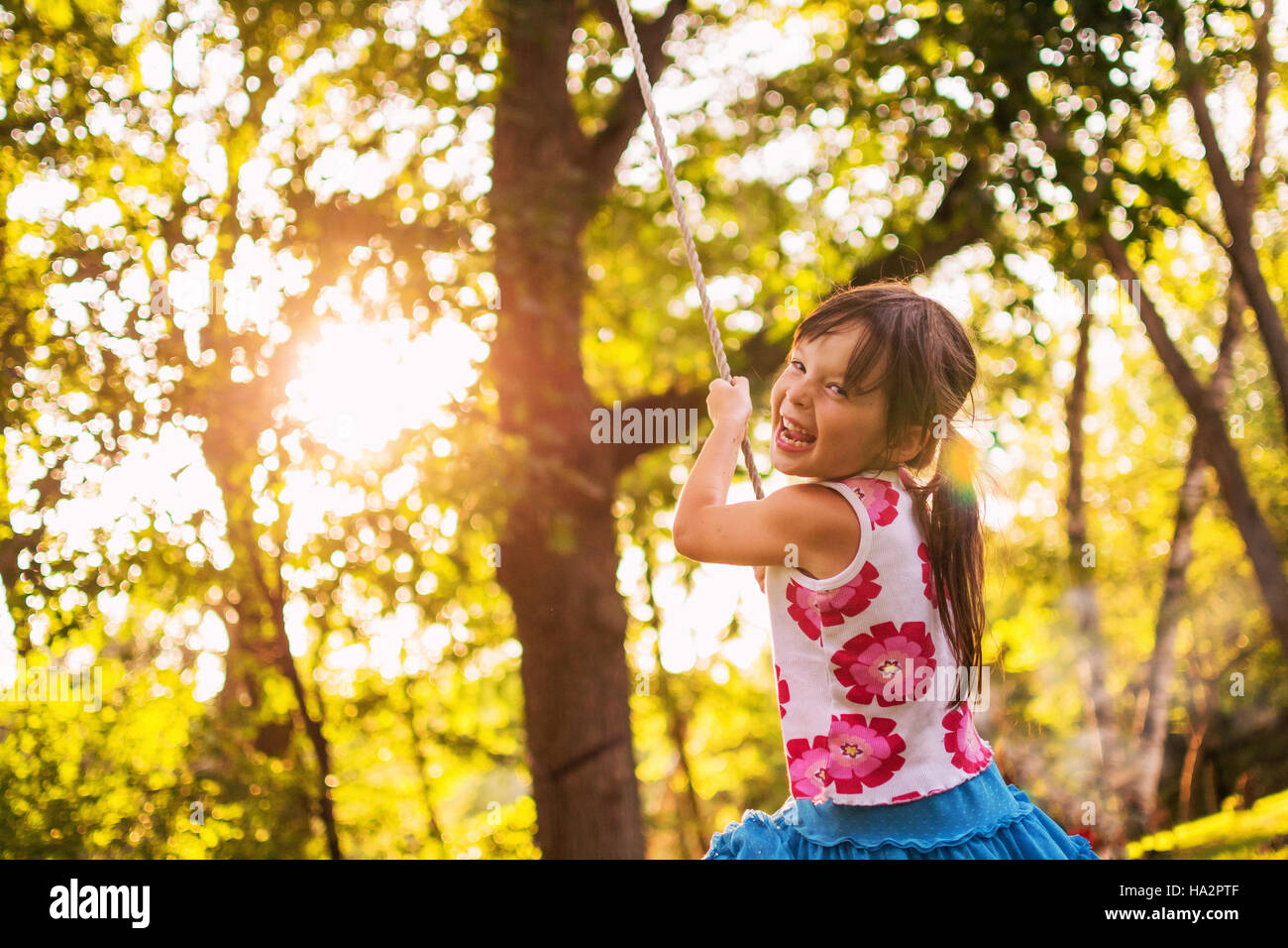 Laughing girl sitting on a rope swing Stock Photo