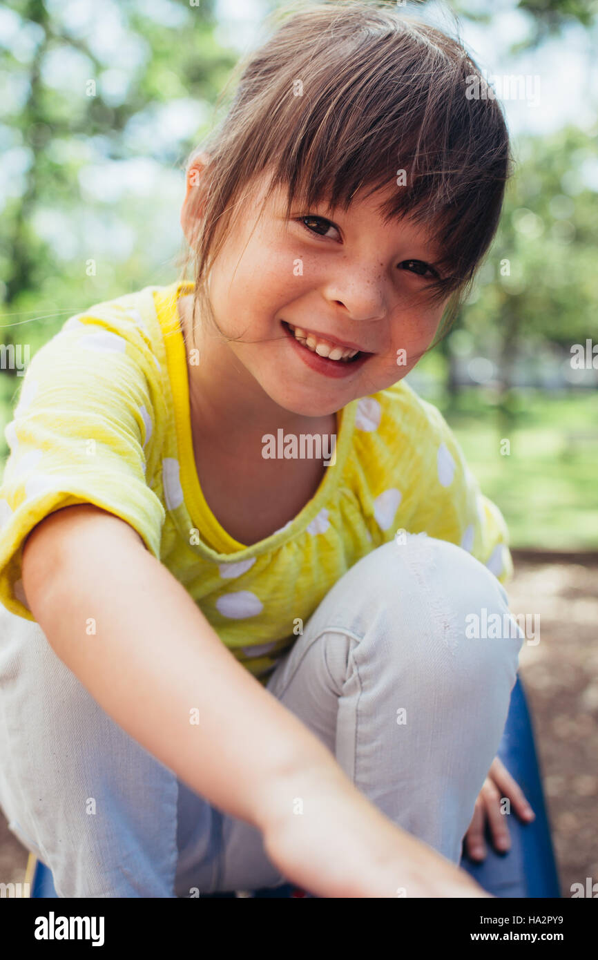 Portrait of a smiling girl sitting on a slide Stock Photo - Alamy