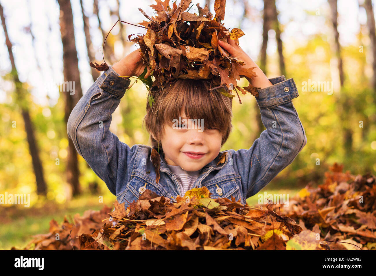 Boy playing in a pile of autumn leaves Stock Photo