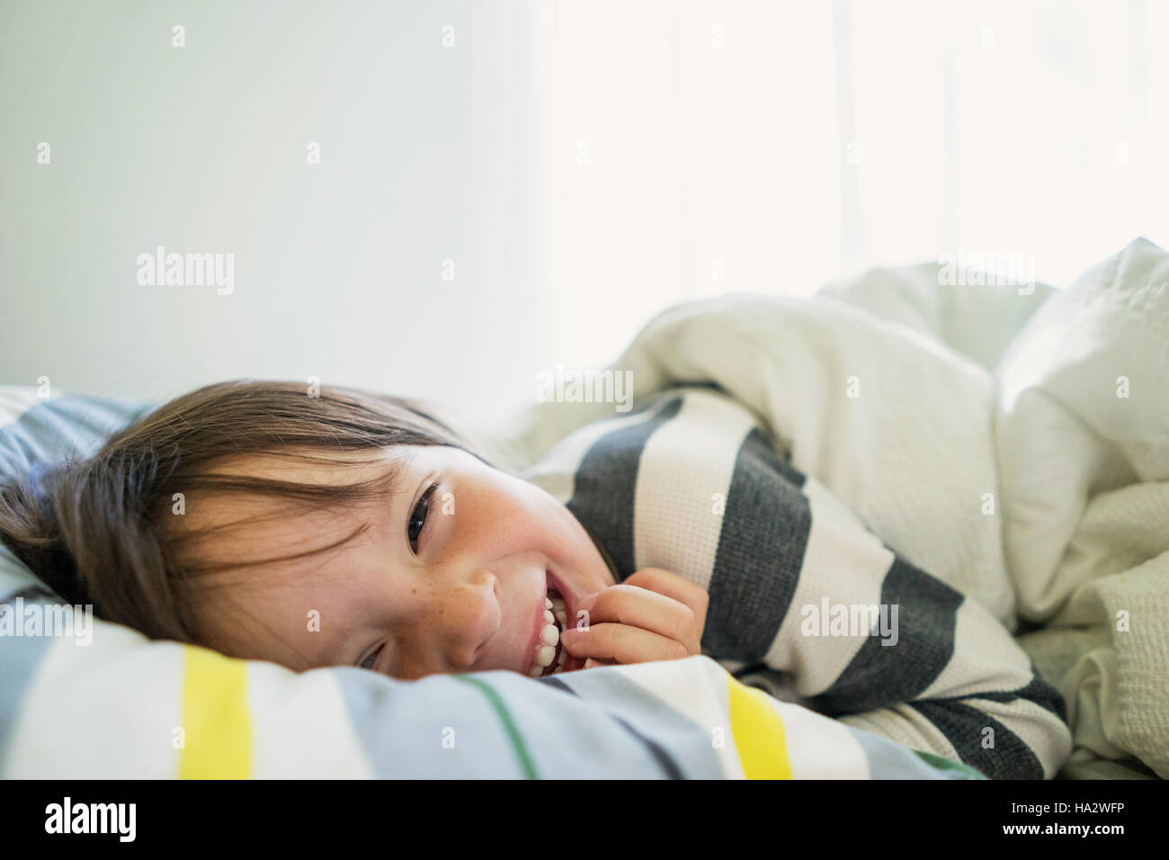 Portrait of a girl lying in bed laughing Stock Photo