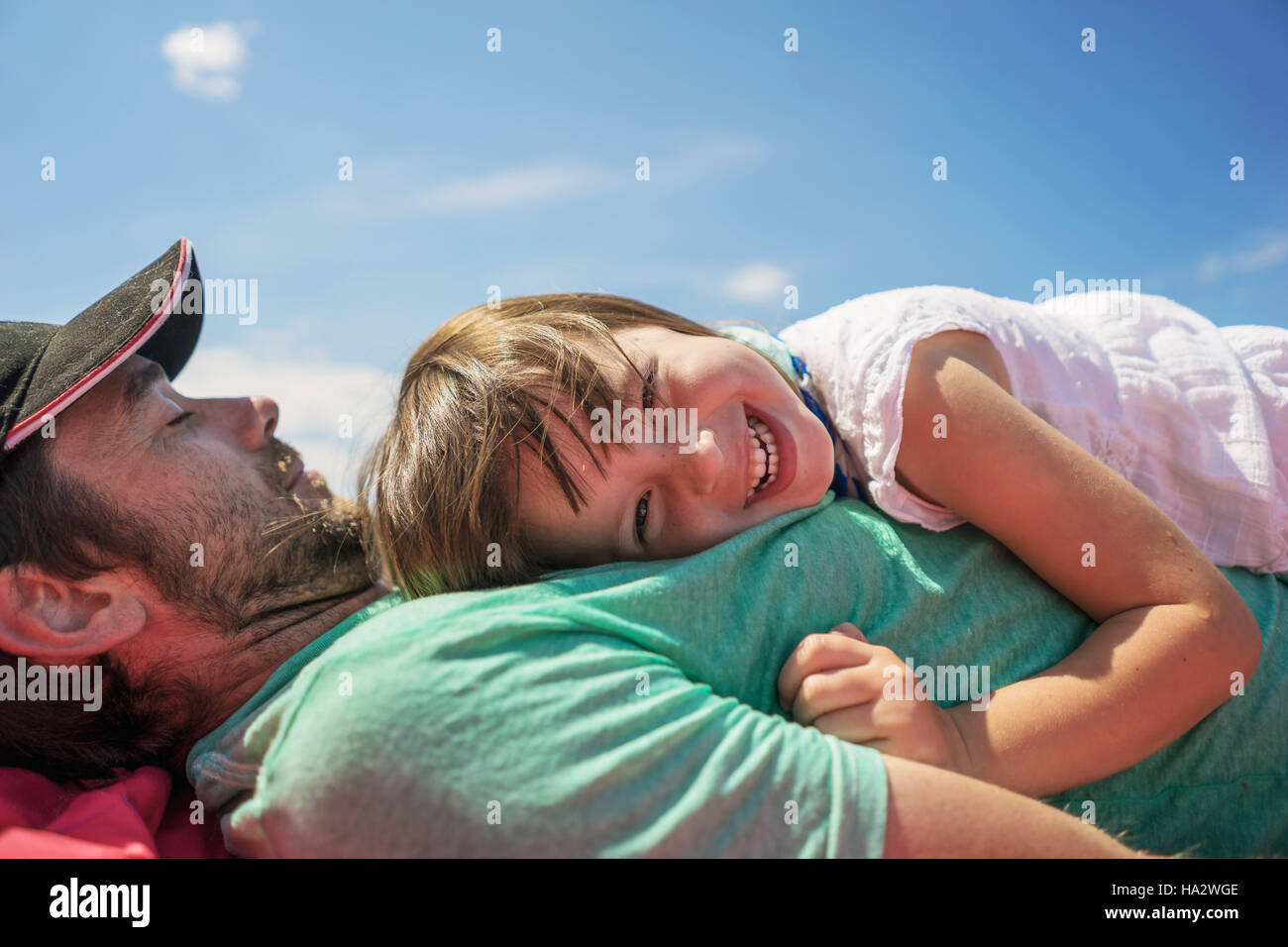 Smiling girl lying on her father's chest Stock Photo