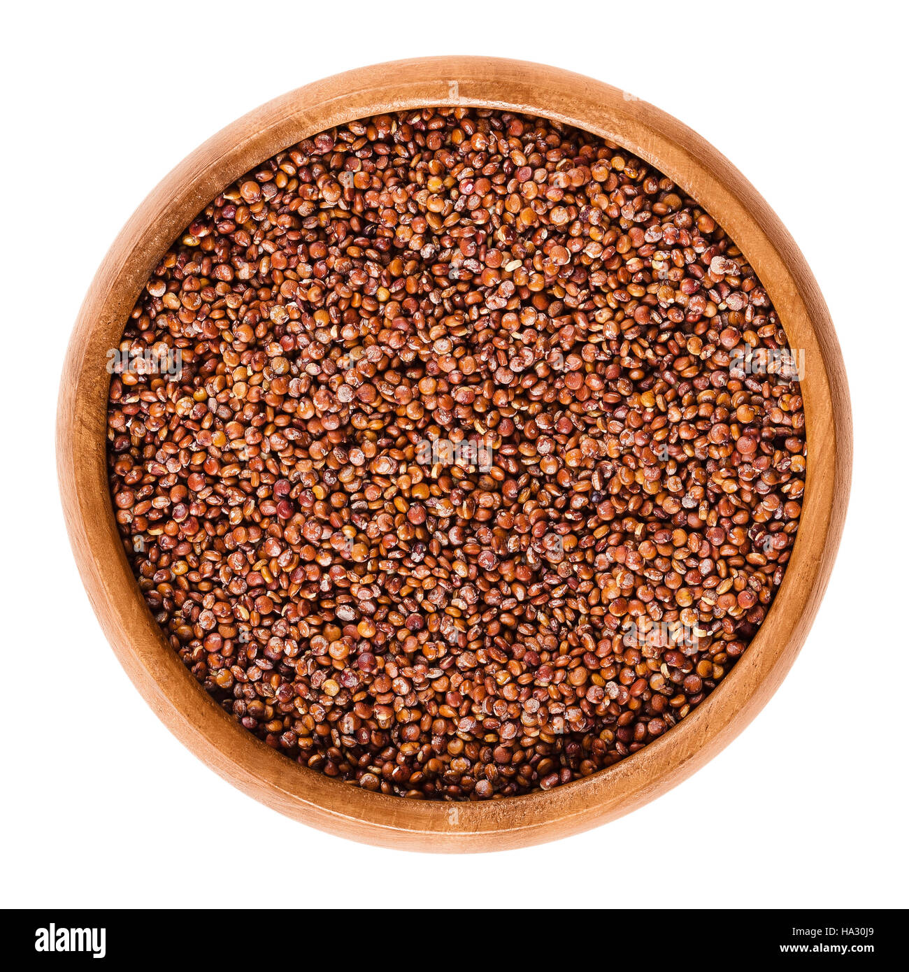 Red quinoa seeds in wooden bowl. Edible fruits of the grain crop Chenopodium quinoa in the Amaranth family is a pseudocereal. Stock Photo