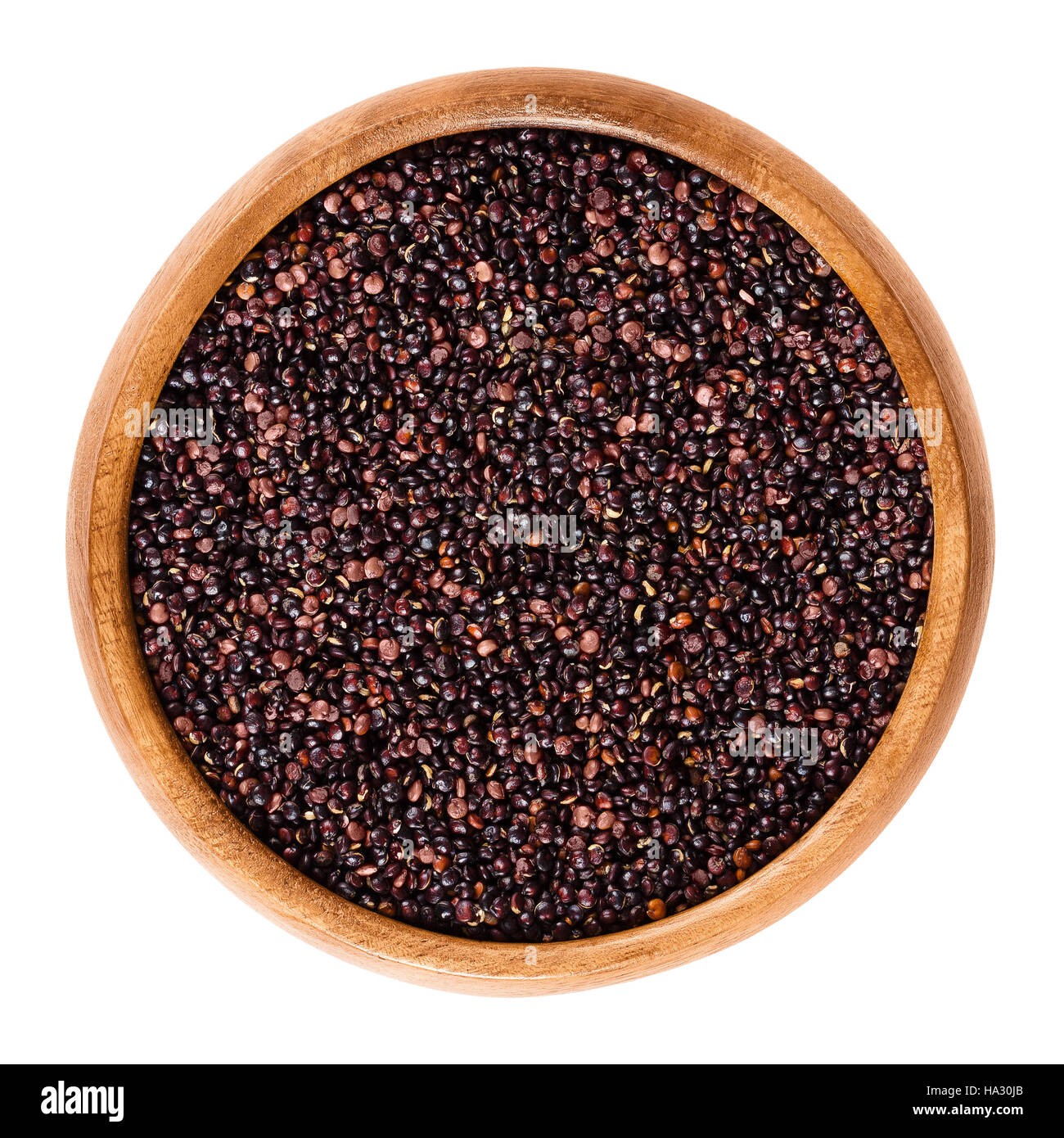 Black quinoa seeds in wooden bowl. Edible fruits of the grain crop Chenopodium quinoa in the Amaranth family is a pseudocereal. Stock Photo