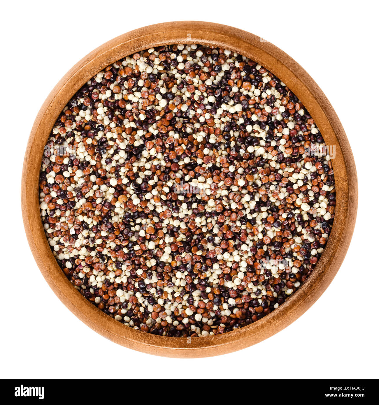 Mixed quinoa seeds in wooden bowl. Yellow, red and black edible fruits of grain crop Chenopodium quinoa in the Amaranth family. Stock Photo