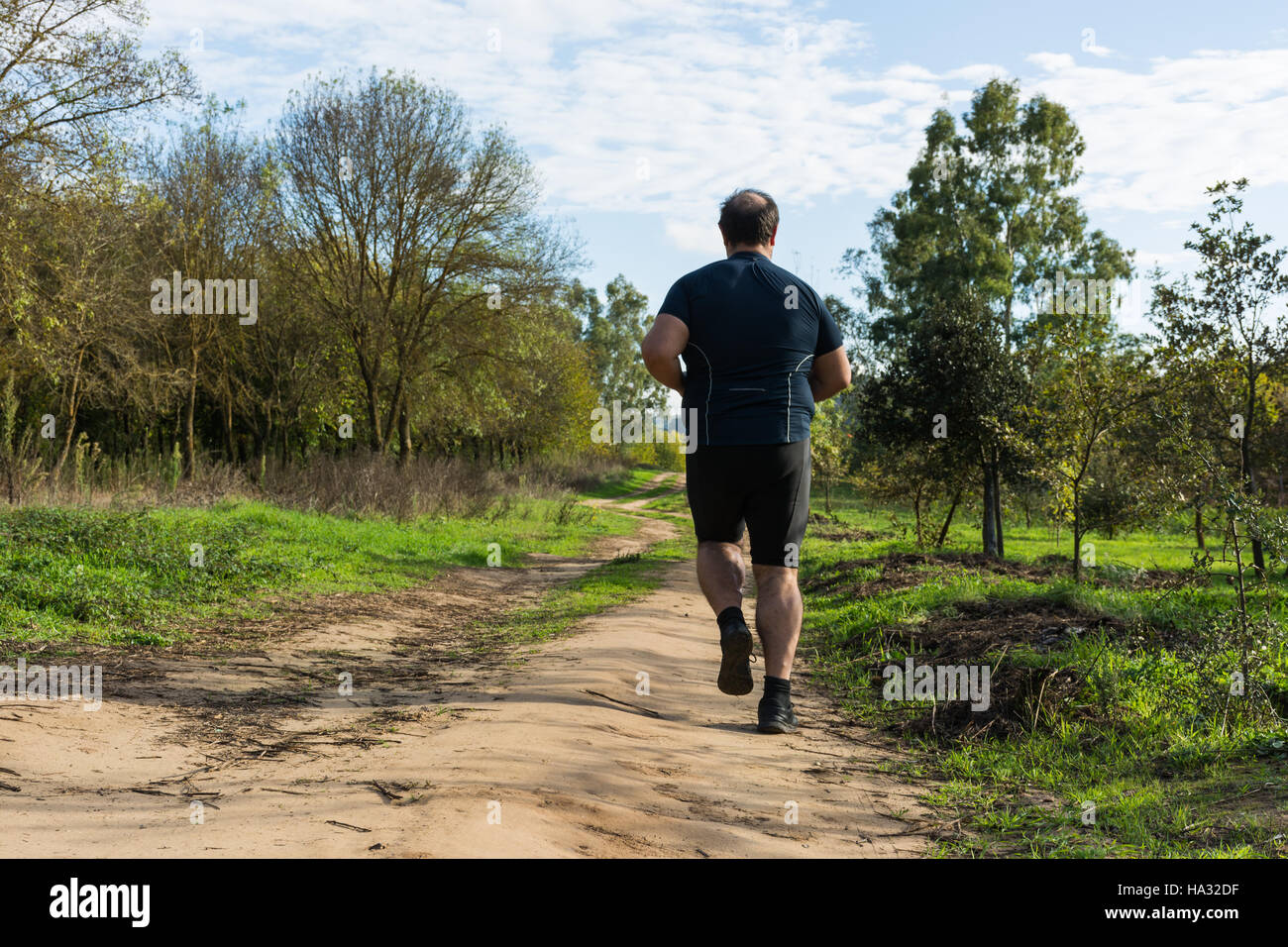 Big belly man jogging , exercising, doing cardio in the park , slightly