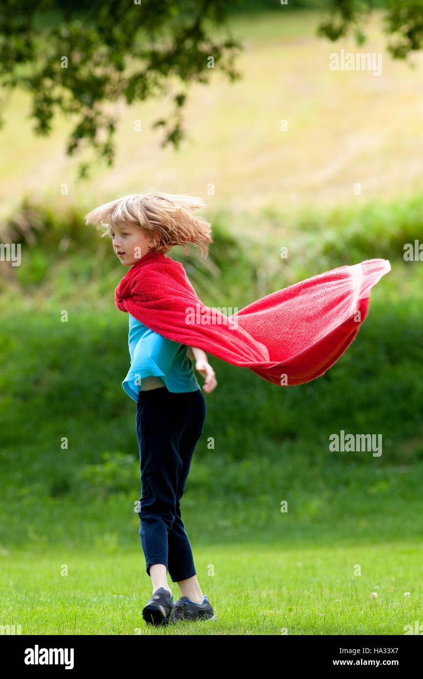 Boy Running Around in Red Towel as Superhero Cloak Stock Photo