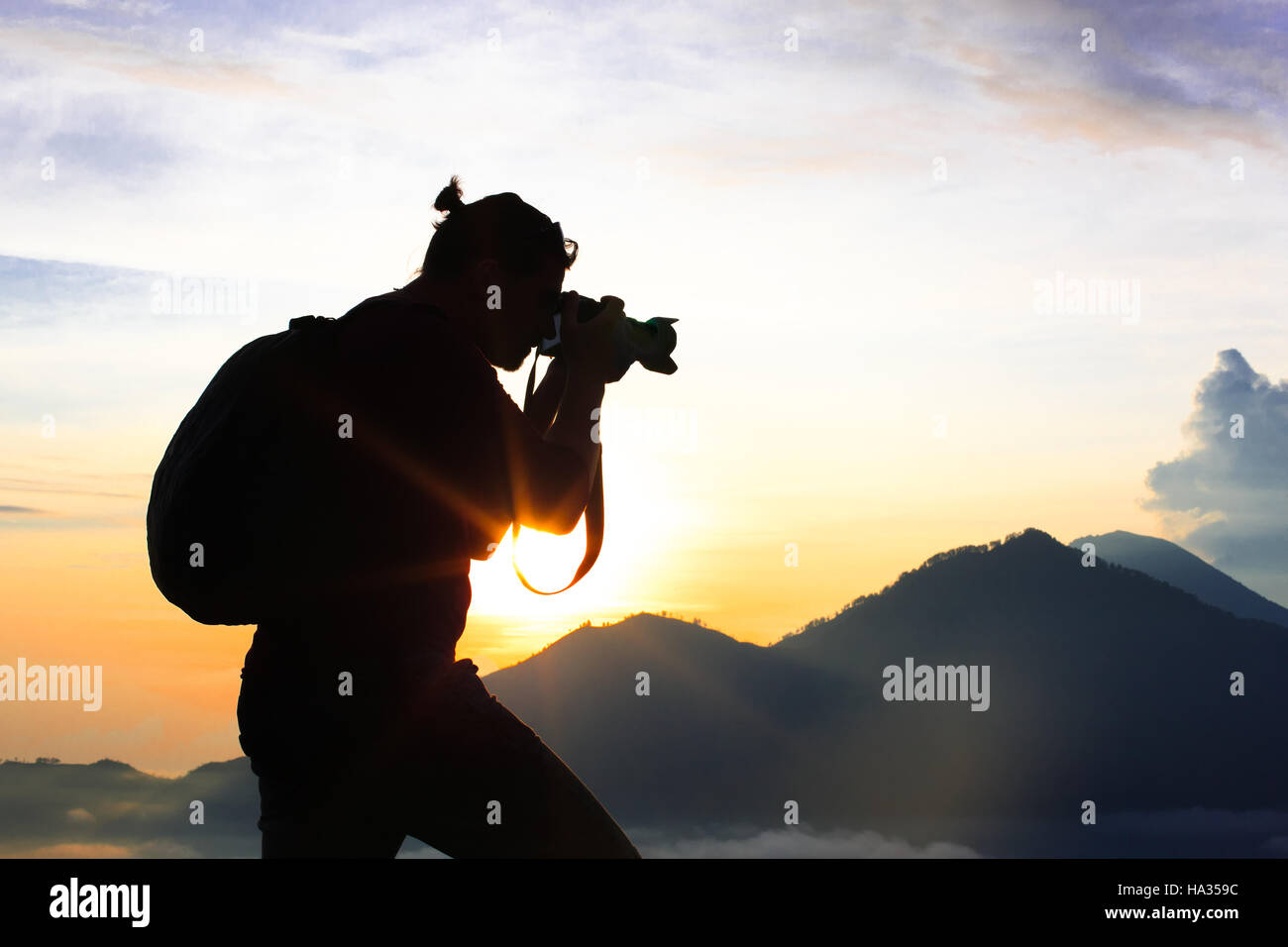 Photographer Hiker walking along, takes pictures and meets sunrise on the mountain Stock Photo