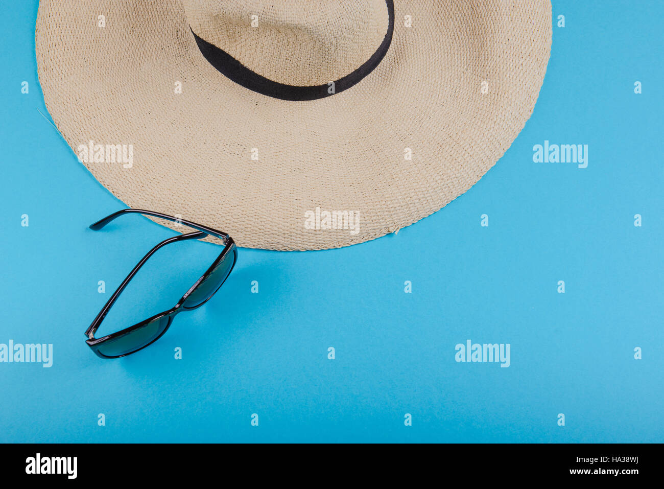 Straw hat and sunglasses on blue background. beach equipment Stock ...