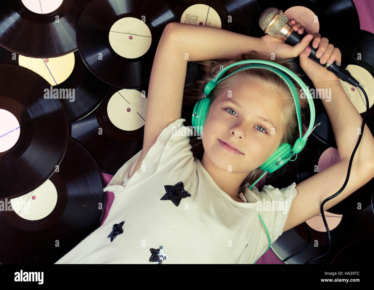 Beautiful Girl Lying Next To Vinyl Records Holding A Microphone And Listening Music On Headphones Top View Stock Photo Alamy