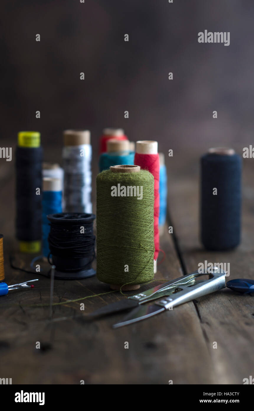 Bobbins with colorful threads on old wooden table background, shallow depth of field. Stock Photo