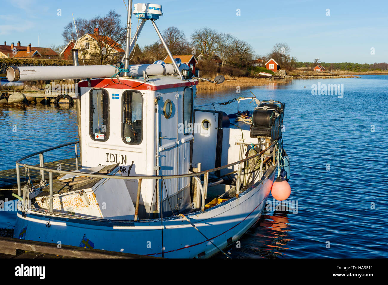 Kristianopel, Sweden - November 24, 2016: Travel documentary of Kristianopel in fall. Small fishing boat in harbor with homes and sheds in background. Stock Photo