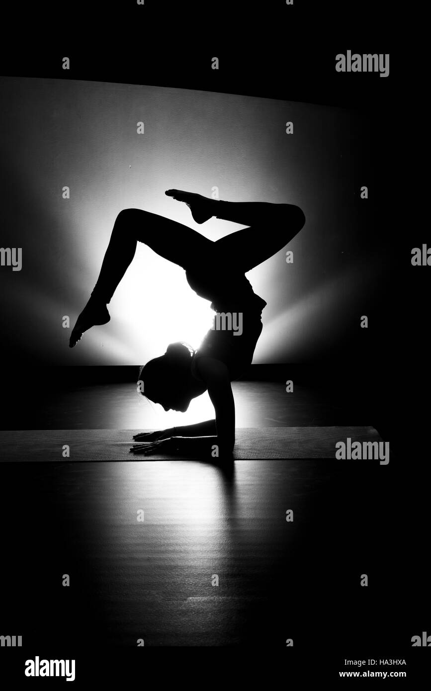 Woman doing yoga forearm stand pose silhouette black and white in studio Stock Photo