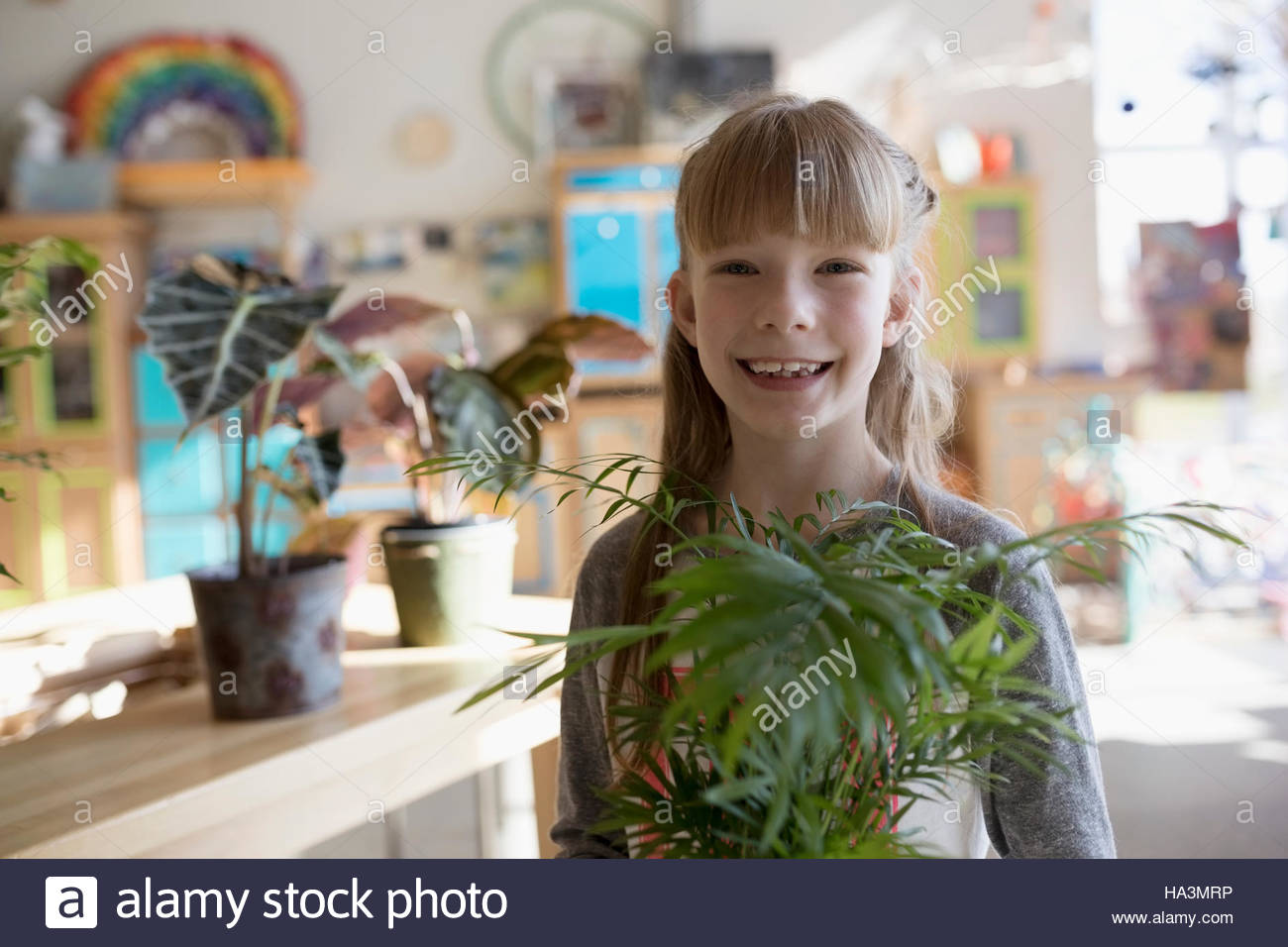 Portrait smiling girl holding plant in science center Stock Photo - Alamy