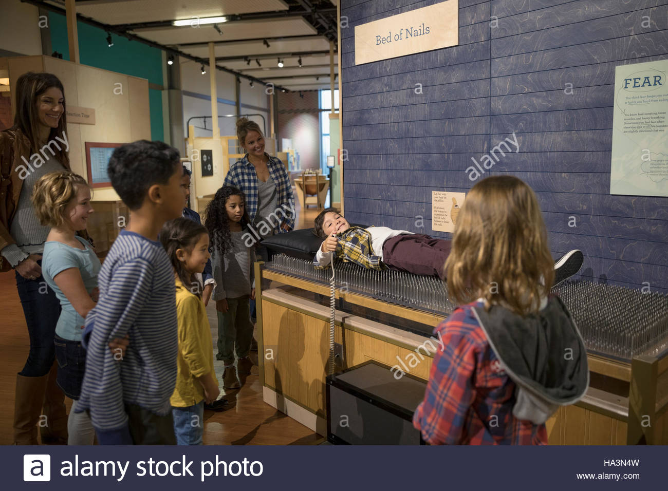 Mothers and children at bed of nails exhibit in science center Stock