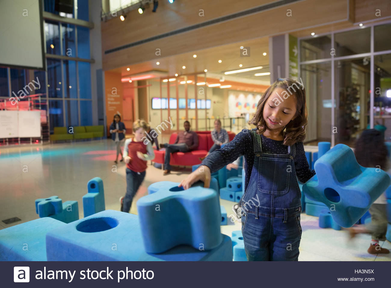 Girl stacking and connecting large pieces in science center Stock Photo