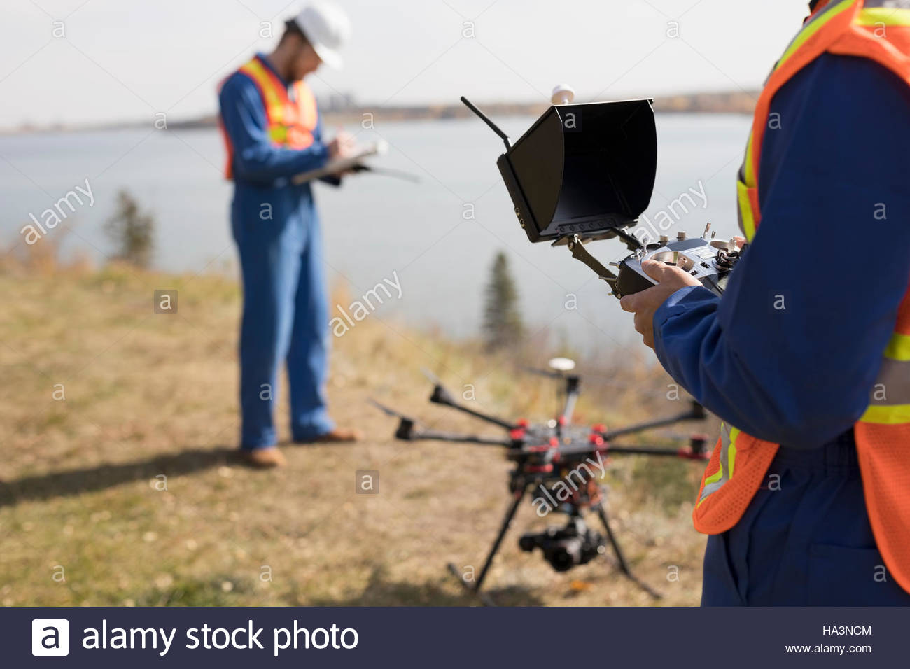 Surveyors with drone equipment at sunny lakeside Stock Photo Alamy