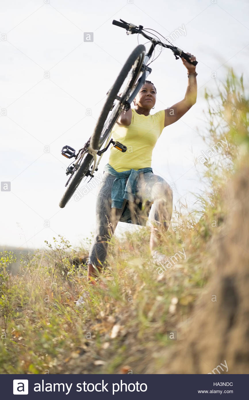 Woman carrying mountain bike uphill Stock Photo Alamy