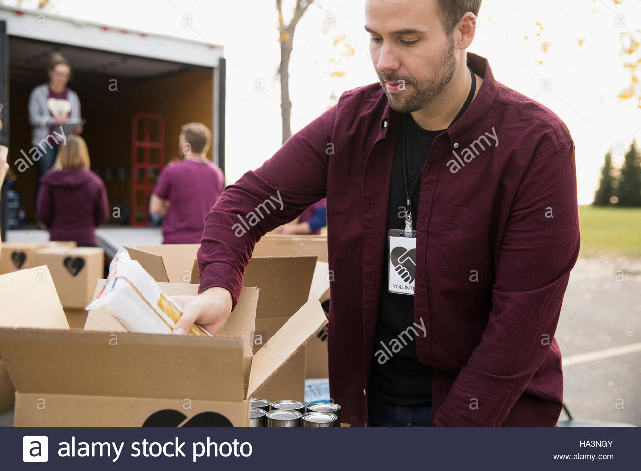 Male volunteer packing food in cardboard box outside truck Stock Photo