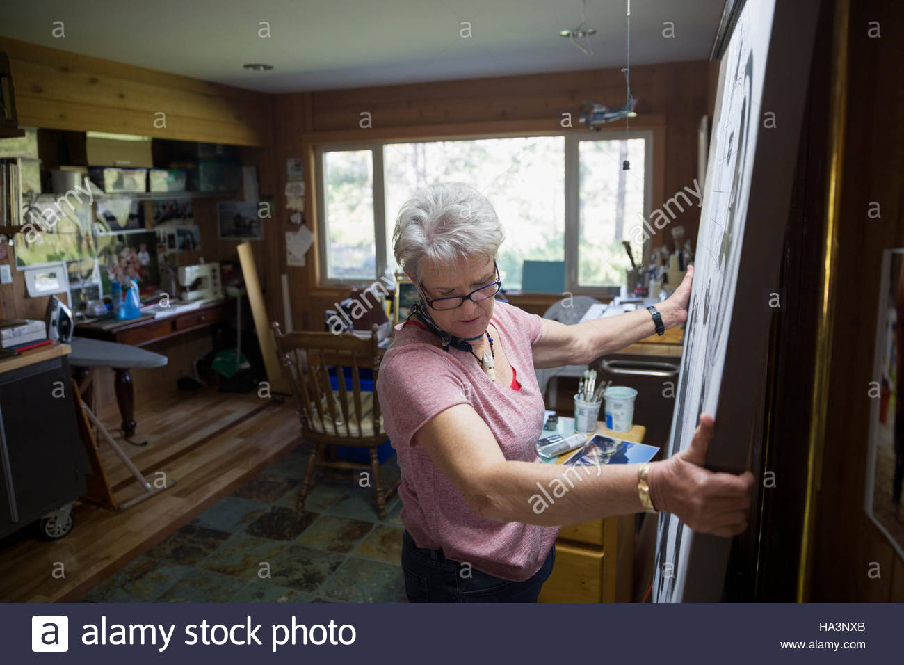 Senior woman artist lifting painting in art studio Stock Photo