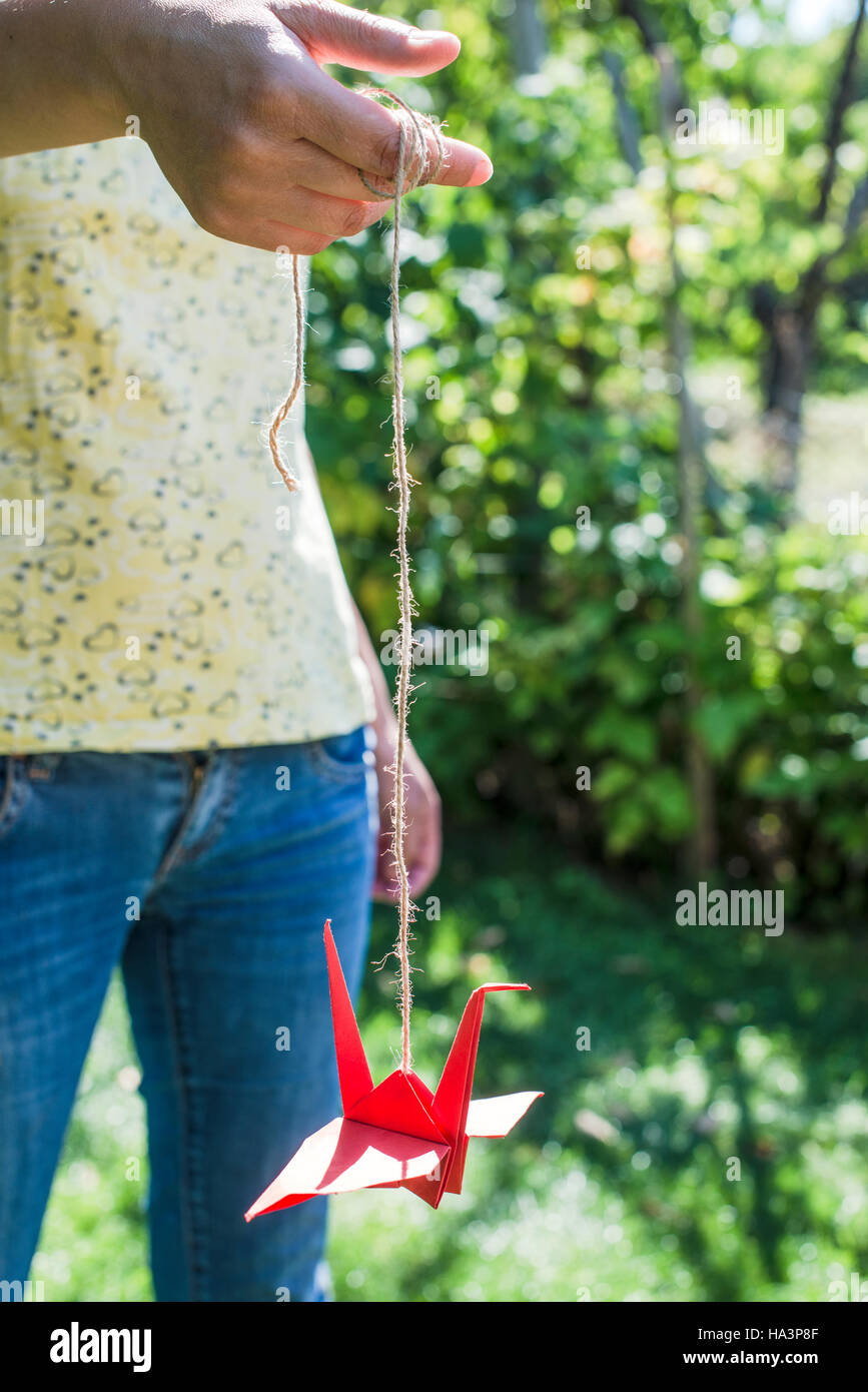 Woman hold red origami crane in the garden Stock Photo