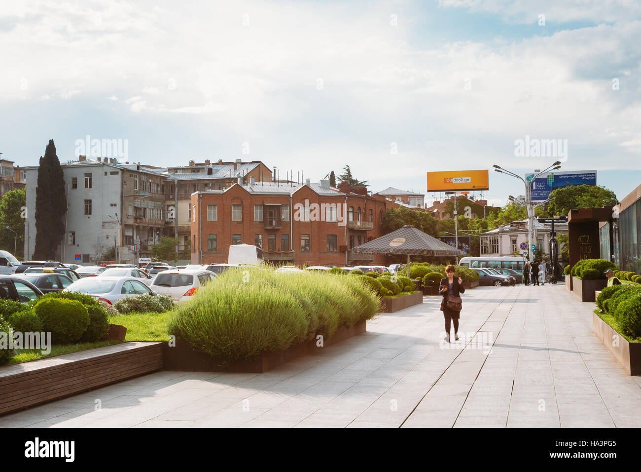 Passerby Woman Walking On Pedestrianized Alley On Rose Revolution Square In Spring Day In Tbilisi, Georgia Stock Photo